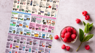 A bowl of raspberries and a flyer on a table.