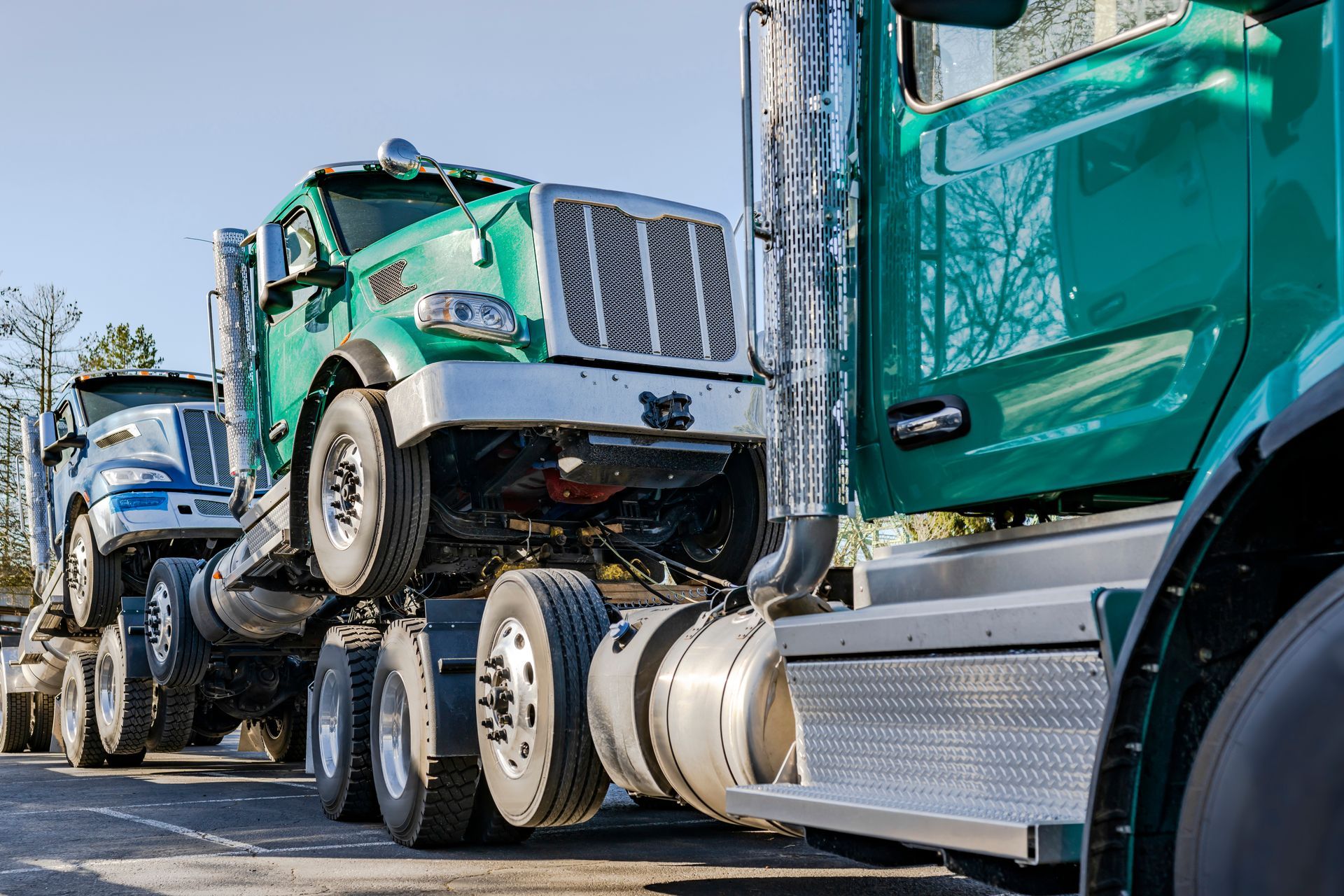 Two green semi trucks are parked next to each other on the side of the road.