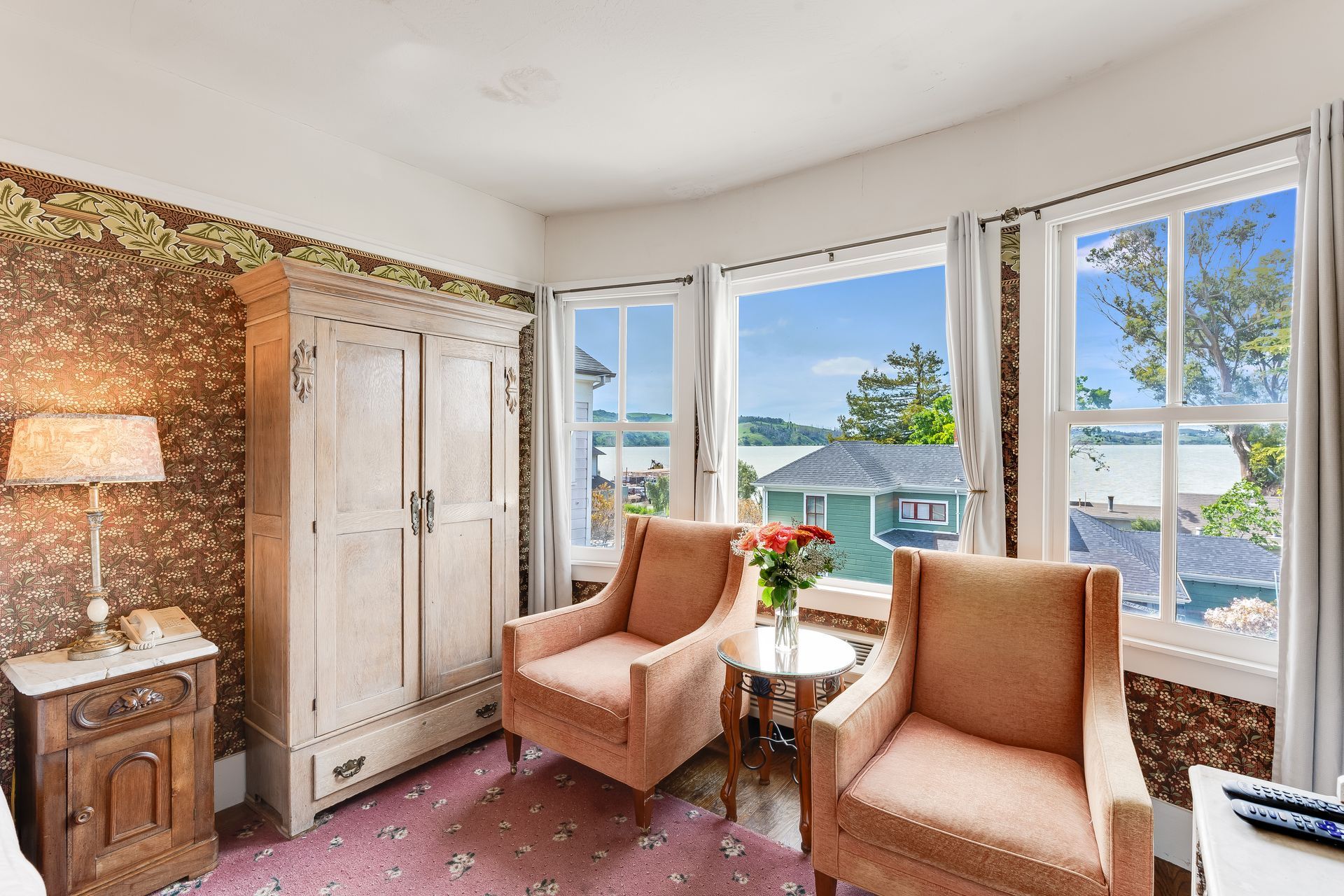Cozy hotel room with antique furniture, two armchairs facing a bay window with a view.