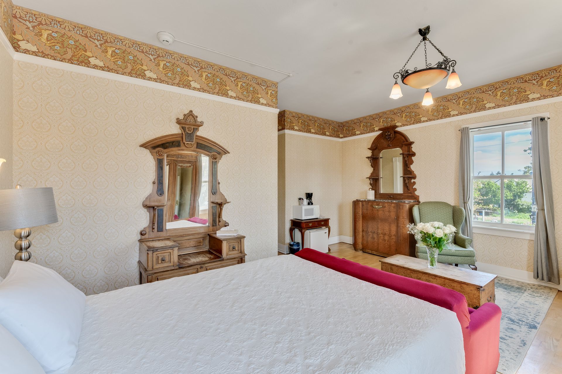 Bedroom with antique furniture, bed, and window with natural light.