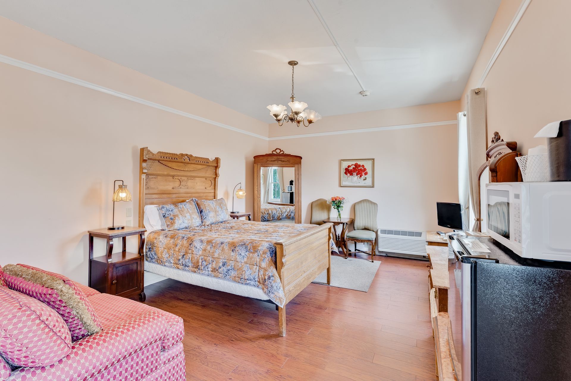 Pink-walled bedroom with bed, couch, dresser, and microwave.