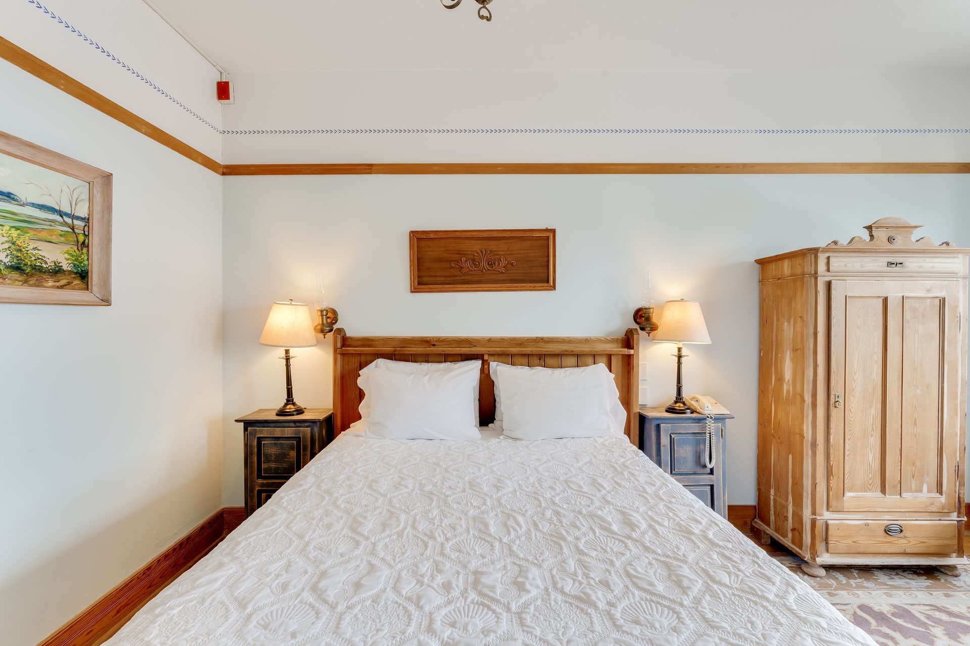 Bedroom with a white bed, wooden furniture, and two lamps.