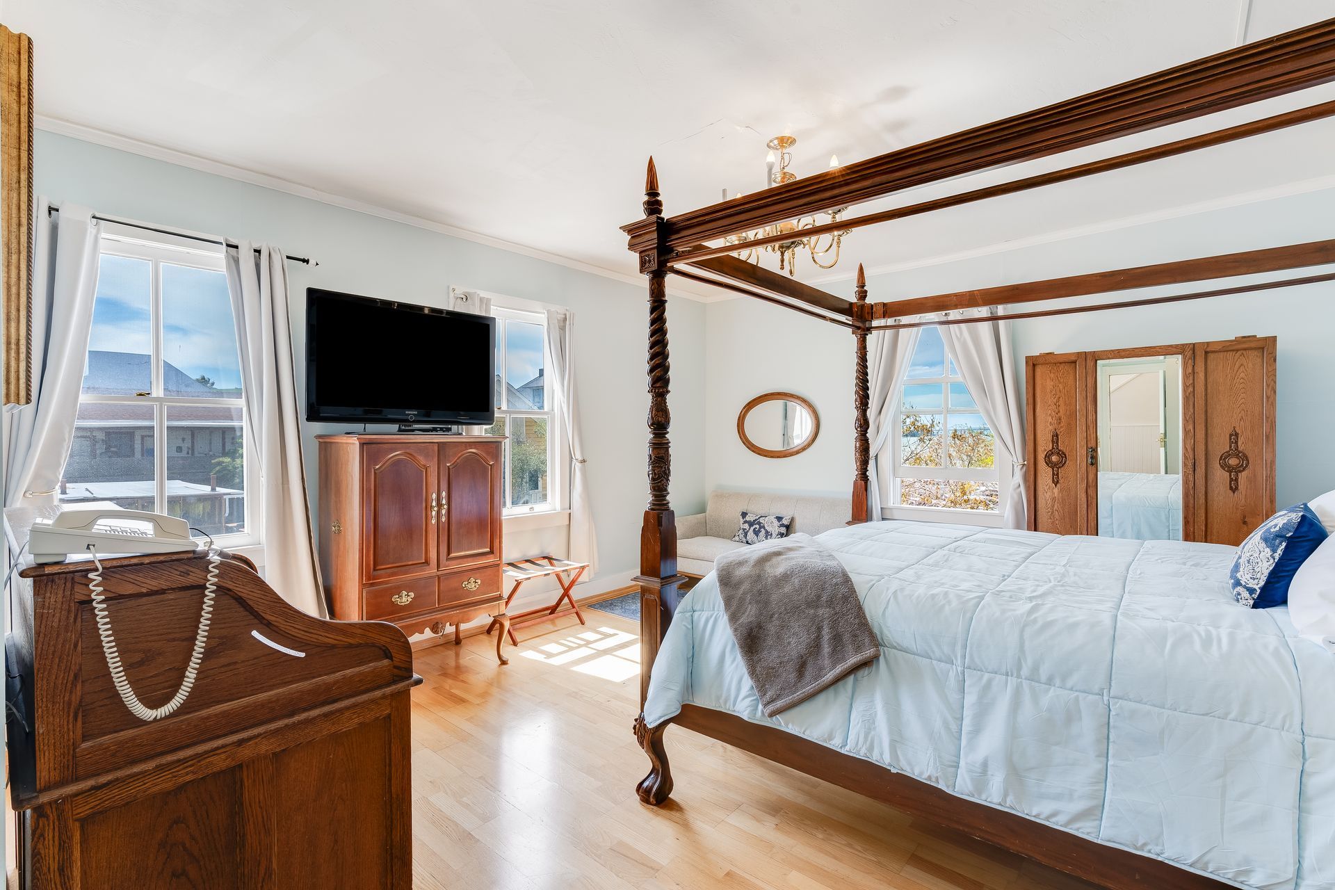 Bedroom with four-poster bed, wooden furniture, TV, and windows with mountain views.
