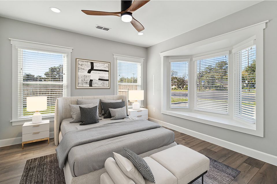 Bedroom with bed, bay window, white nightstands, and abstract art.