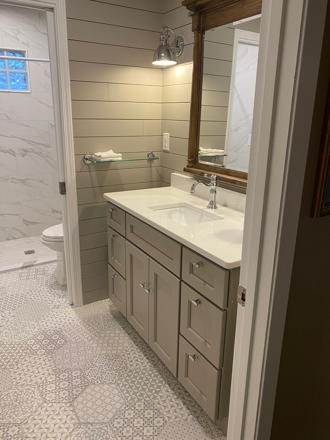 Bathroom with vanity, mirror, and tiled floor, adjacent to a shower.