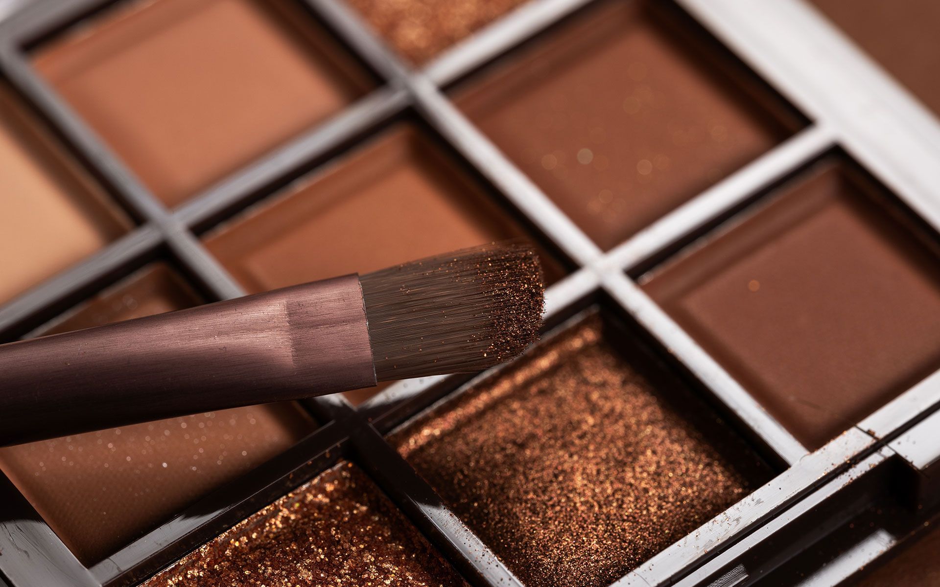 Eyeshadow palette with a makeup brush, various shades of brown.