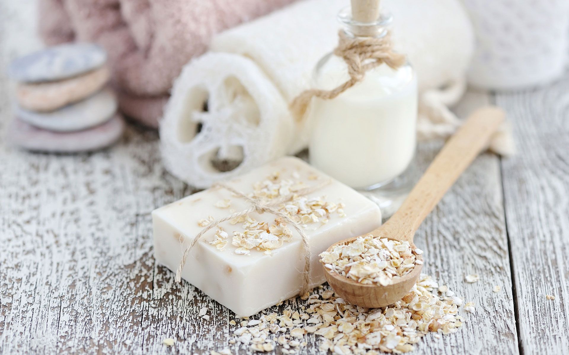 Soap, oats, bath products on white wooden surface.