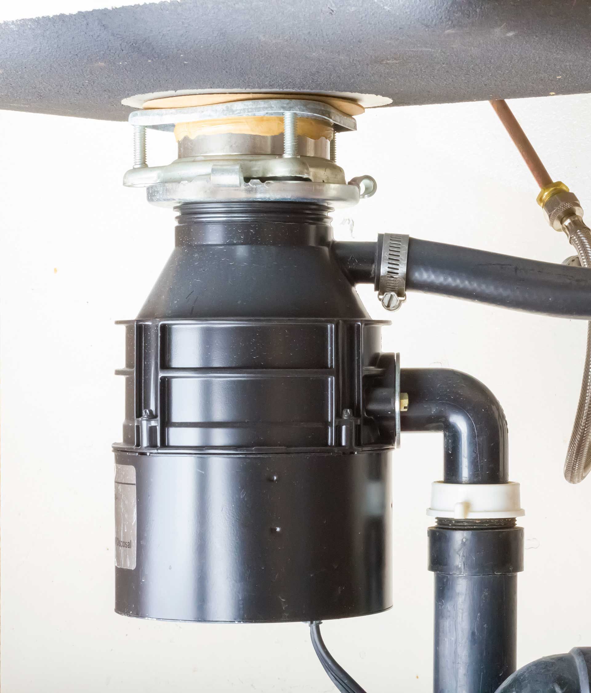 A garbage disposal is sitting under a sink in a kitchen.