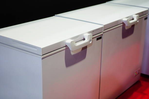 Three white freezers are sitting next to each other on a red carpet.