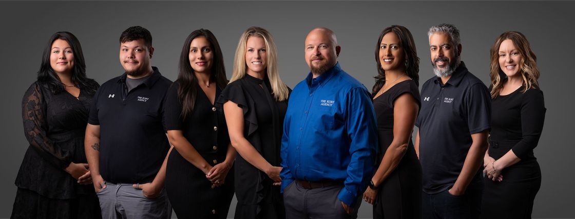 Seven people stand in a studio, smiling and posing against a black background.