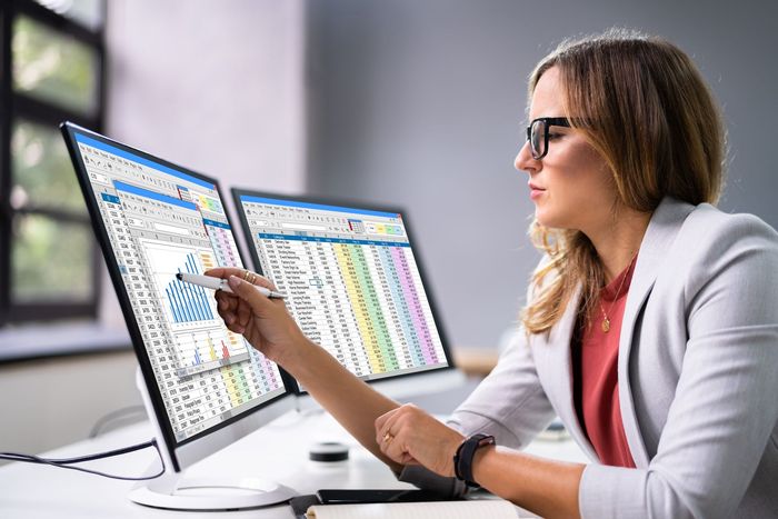 A woman is sitting at a desk looking at a computer screen.