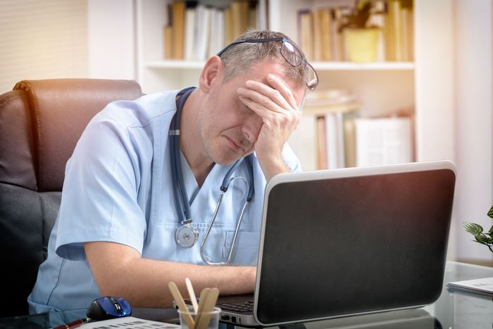 A doctor is sitting at a desk in front of a laptop computer.