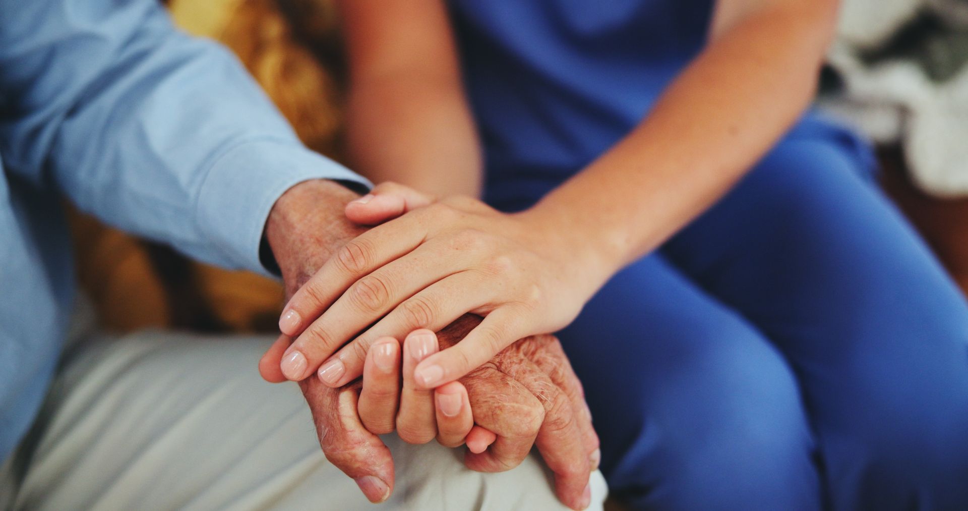A nurse is holding the hands of an elderly man.