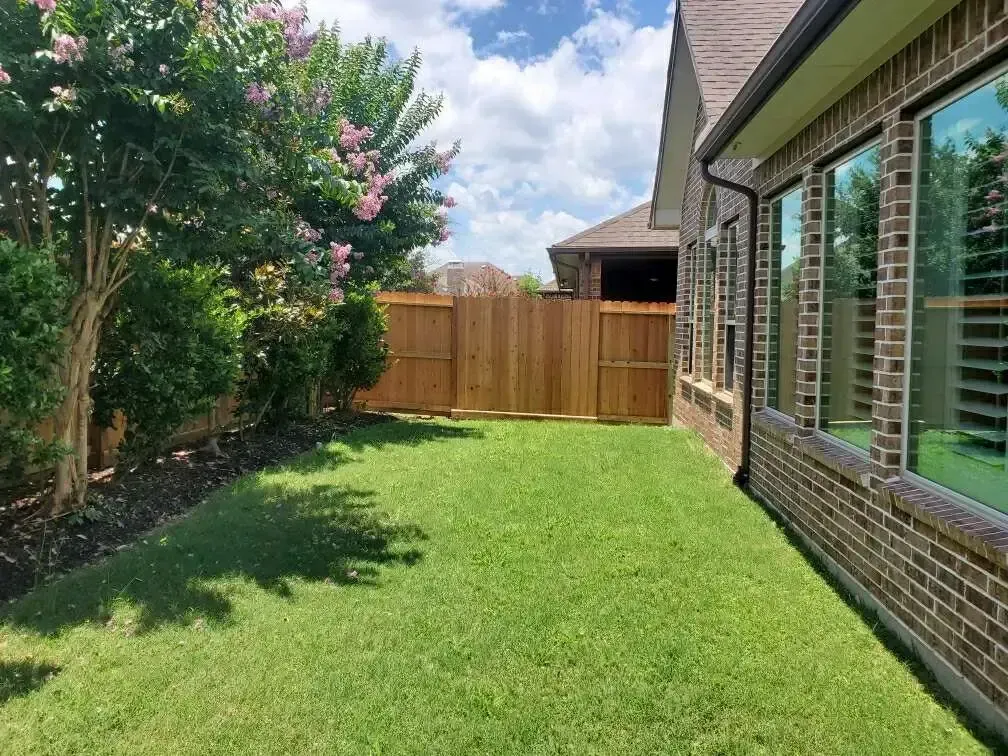 There is a wooden fence in the backyard of a house.