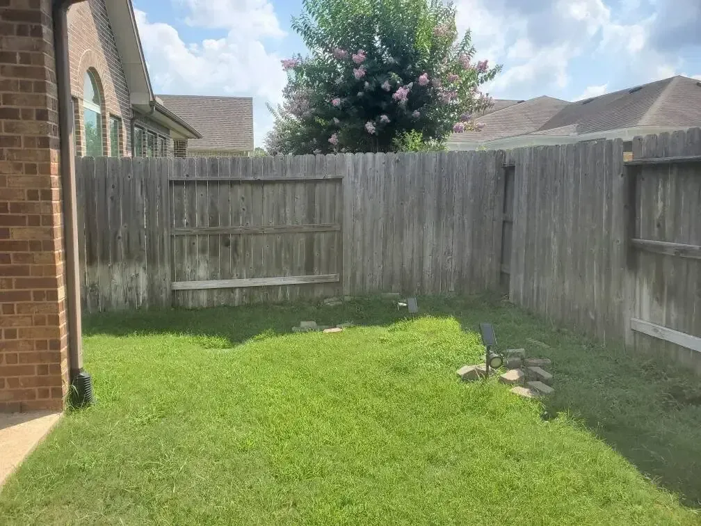 There is a wooden fence in the backyard of a house.