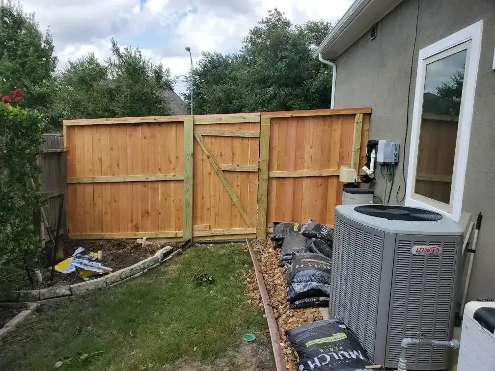 A wooden fence is being built in the backyard of a house.