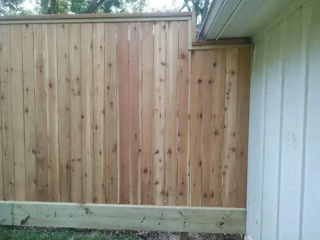 A wooden fence is sitting next to a white house.