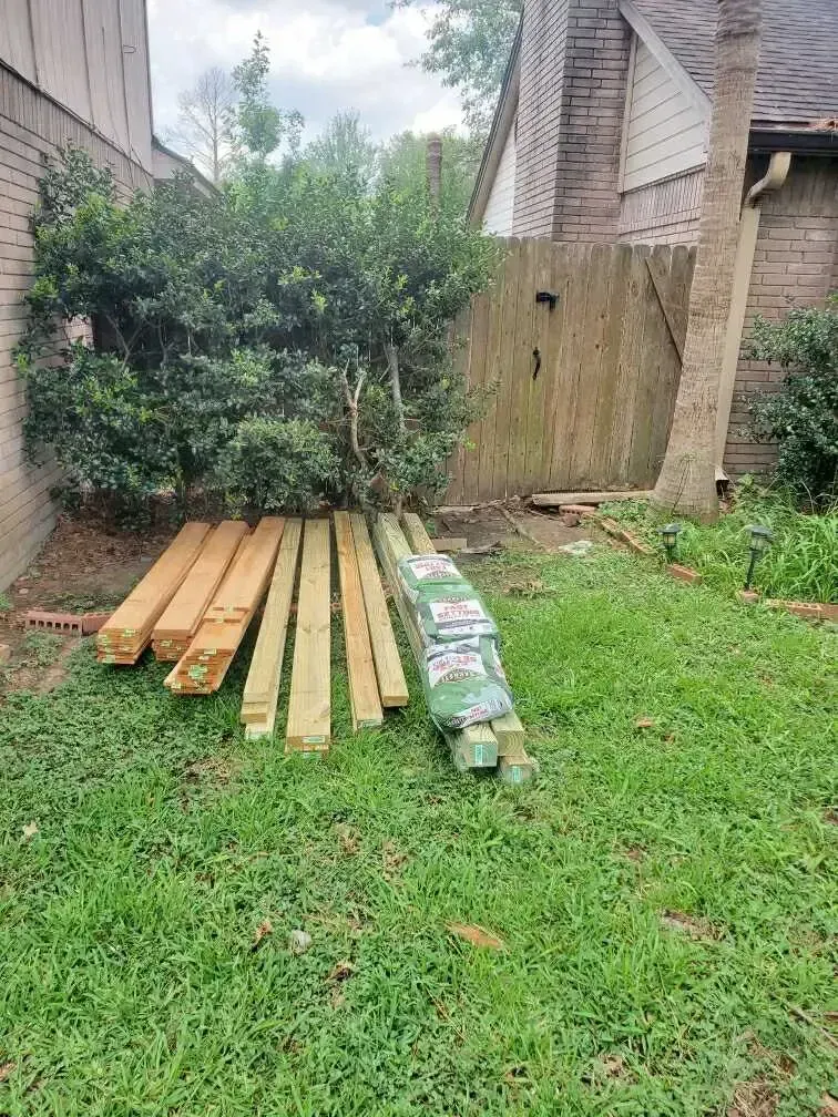 A pile of wood is sitting in the grass in front of a house.