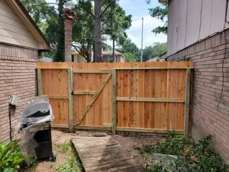 A wooden fence with a gate in the backyard of a house.