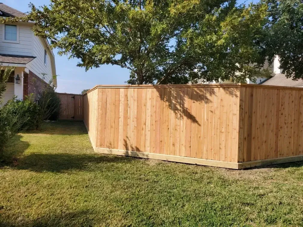 A wooden fence is in the backyard of a house.