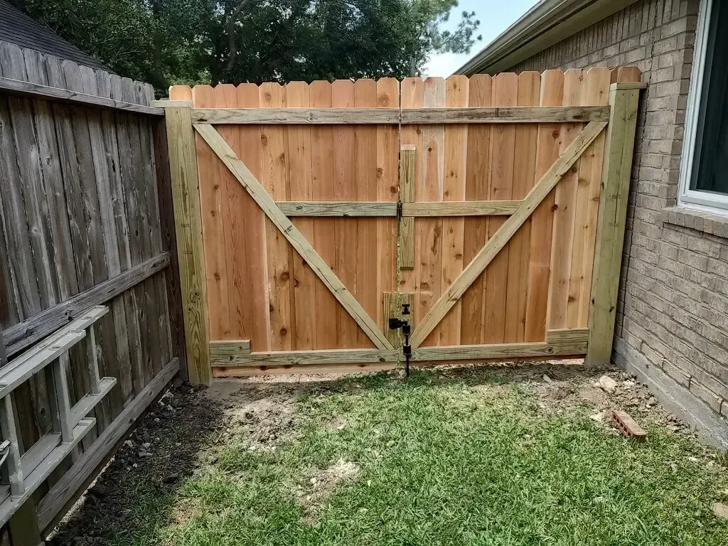 A wooden fence with a gate in the backyard of a house.