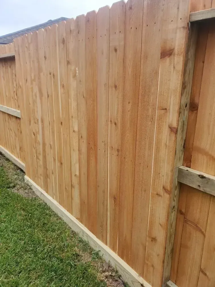 A wooden fence is sitting on top of a lush green field.