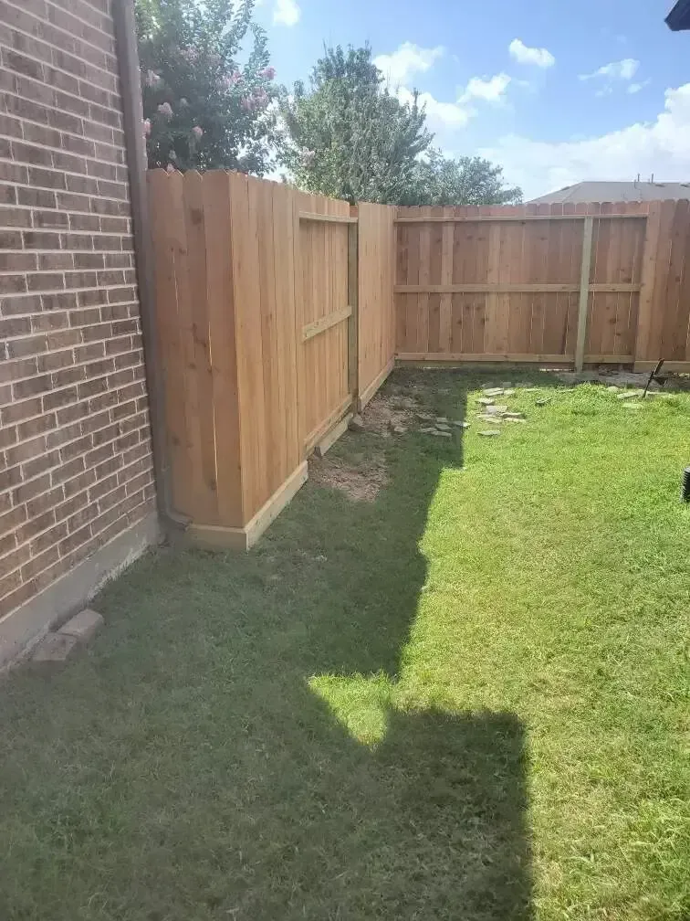 A wooden fence is in the backyard of a house.