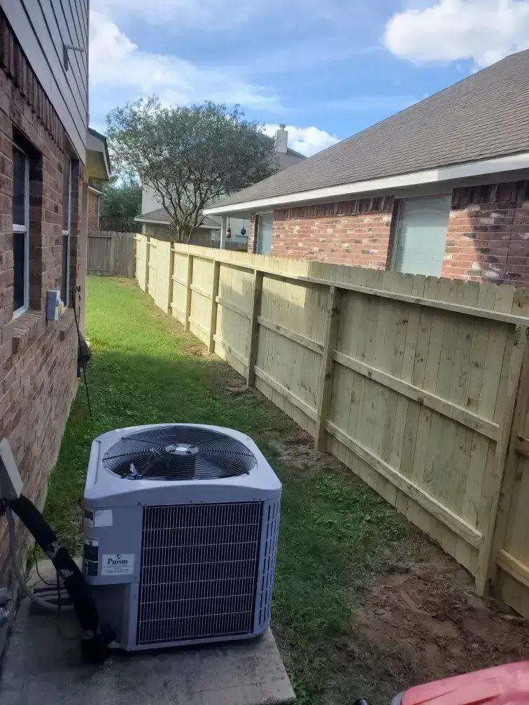 A wooden fence with an air conditioner in the backyard of a house.