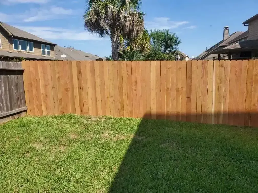 A wooden fence is in the backyard of a house.