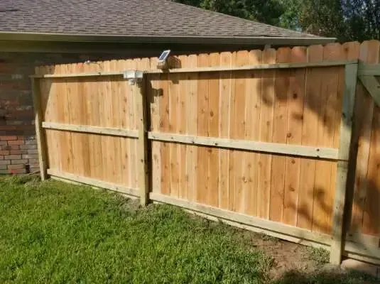 A wooden fence is in the backyard of a house.