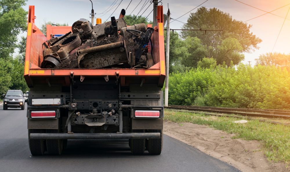 Orange dump truck filled with scrap metal driving on a road.