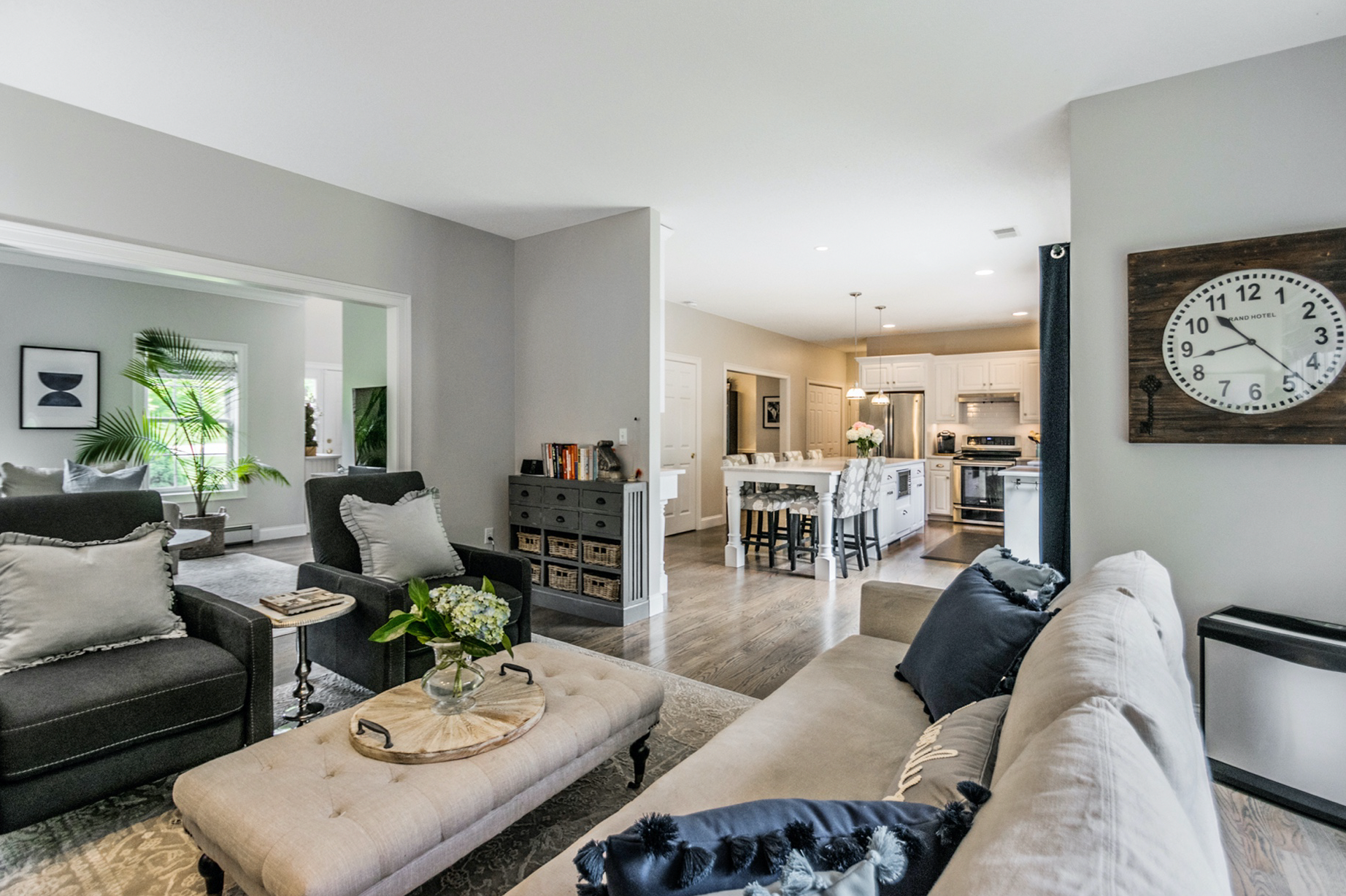 A living room with a couch , chairs , ottoman and a mirror