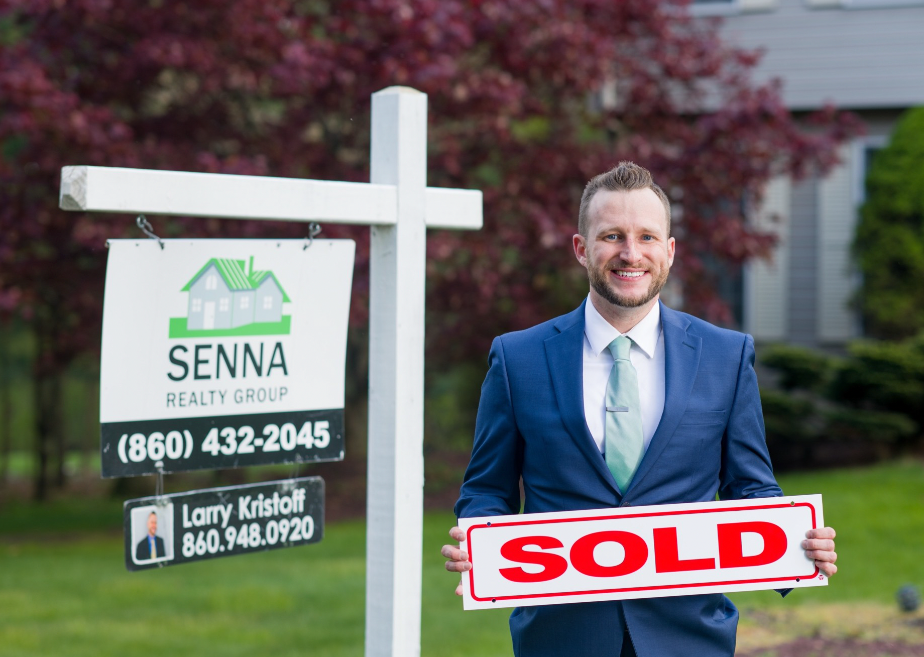 Two men shaking hands in front of a for sale sign