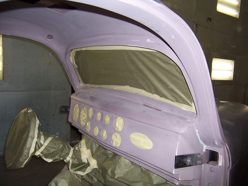 Purple car body in a workshop, masked and prepped for repainting with doors removed