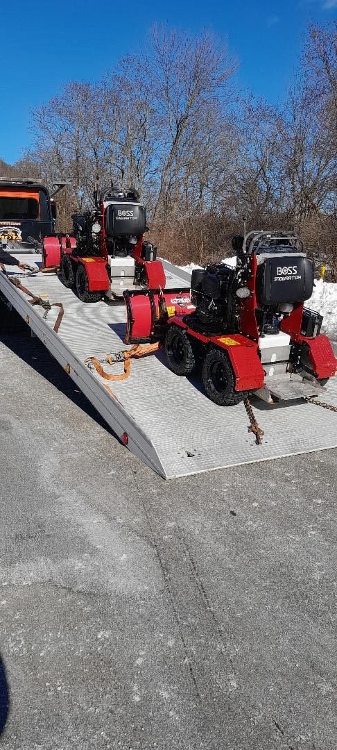 Two snow blowers are sitting on top of a ramp in the snow.