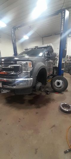 A truck is sitting on a lift in a garage.