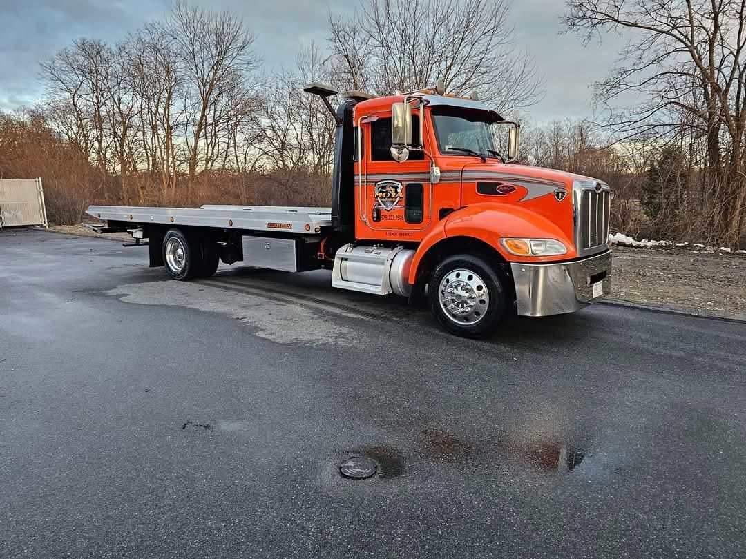 An orange tow truck is parked on the side of the road.