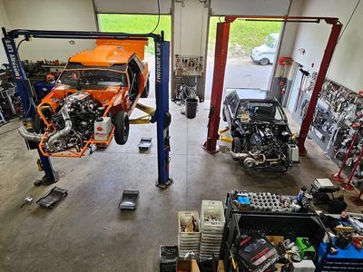 Two cars are being worked on in a garage.