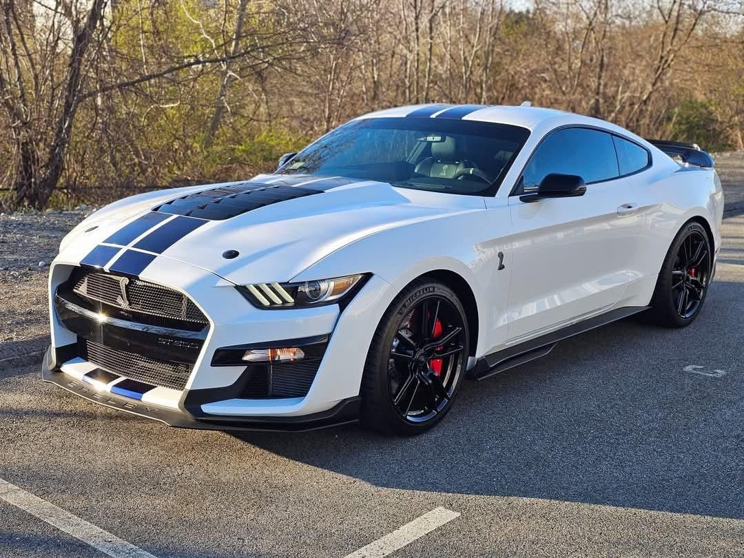 A white ford mustang gt500 is parked in a parking lot.