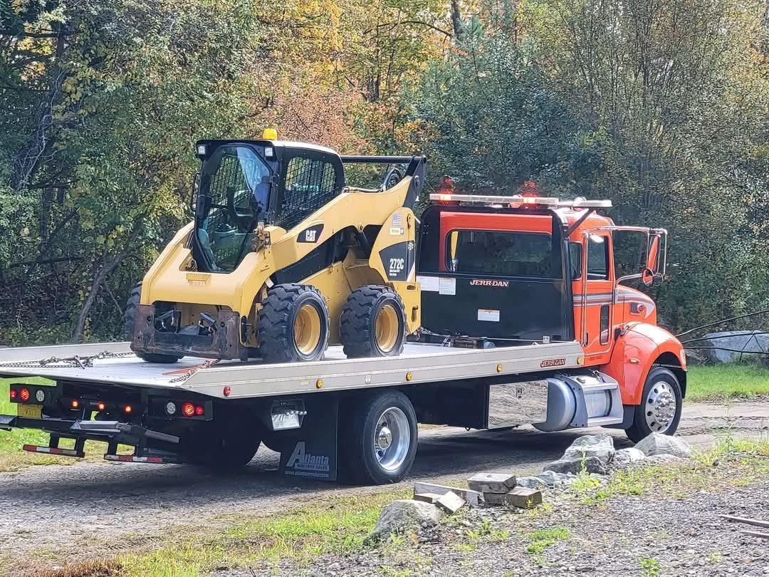 A tow truck with a bulldozer on the back of it.