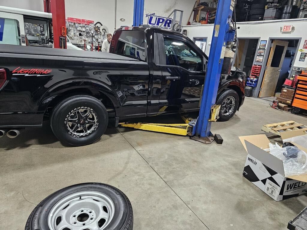 A black truck is sitting on a lift in a garage.