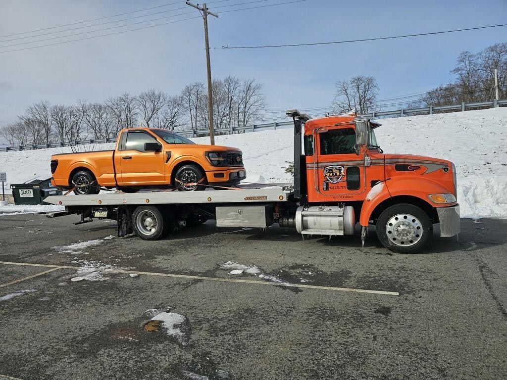 A tow truck is towing a pickup truck in the snow.