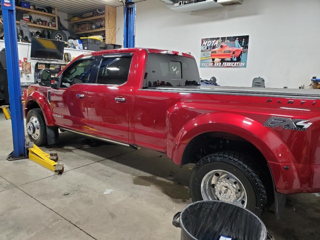 A red truck is parked on a lift in a garage.