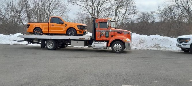 A tow truck is carrying a ford f150 on the back of it.