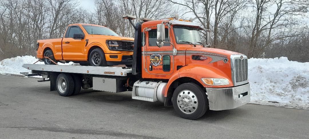 A tow truck with two cars on the back of it.