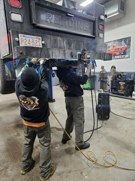Two men are working on a truck in a garage.