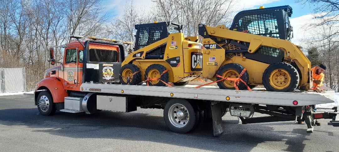 A tow truck is carrying a bulldozer on the back of it.