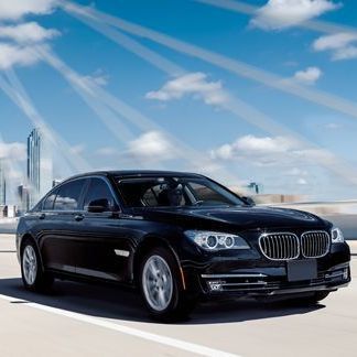 Black BMW sedan driving on a bridge under a blue sky