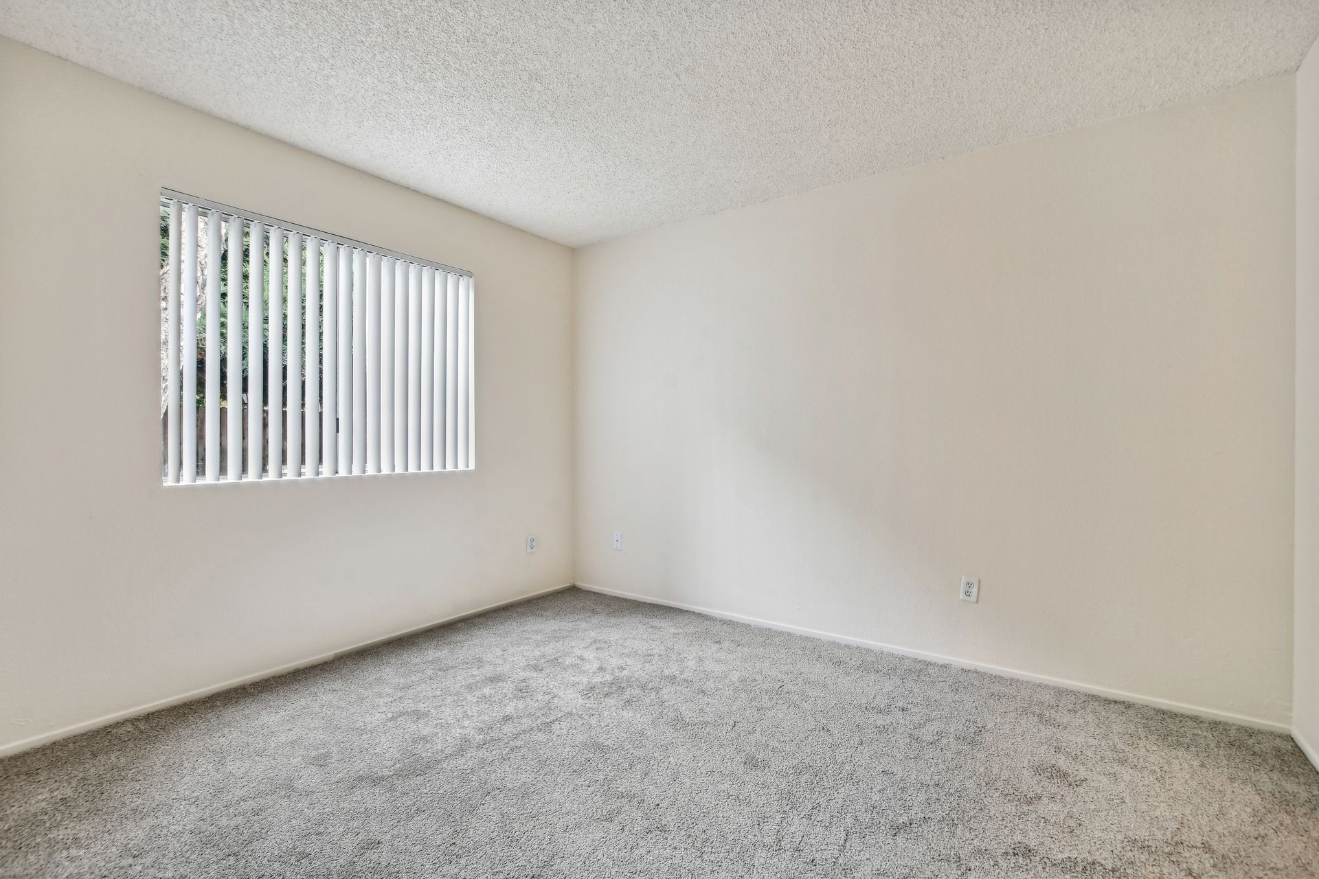 Empty room with gray carpet, white walls, and a window with blinds.