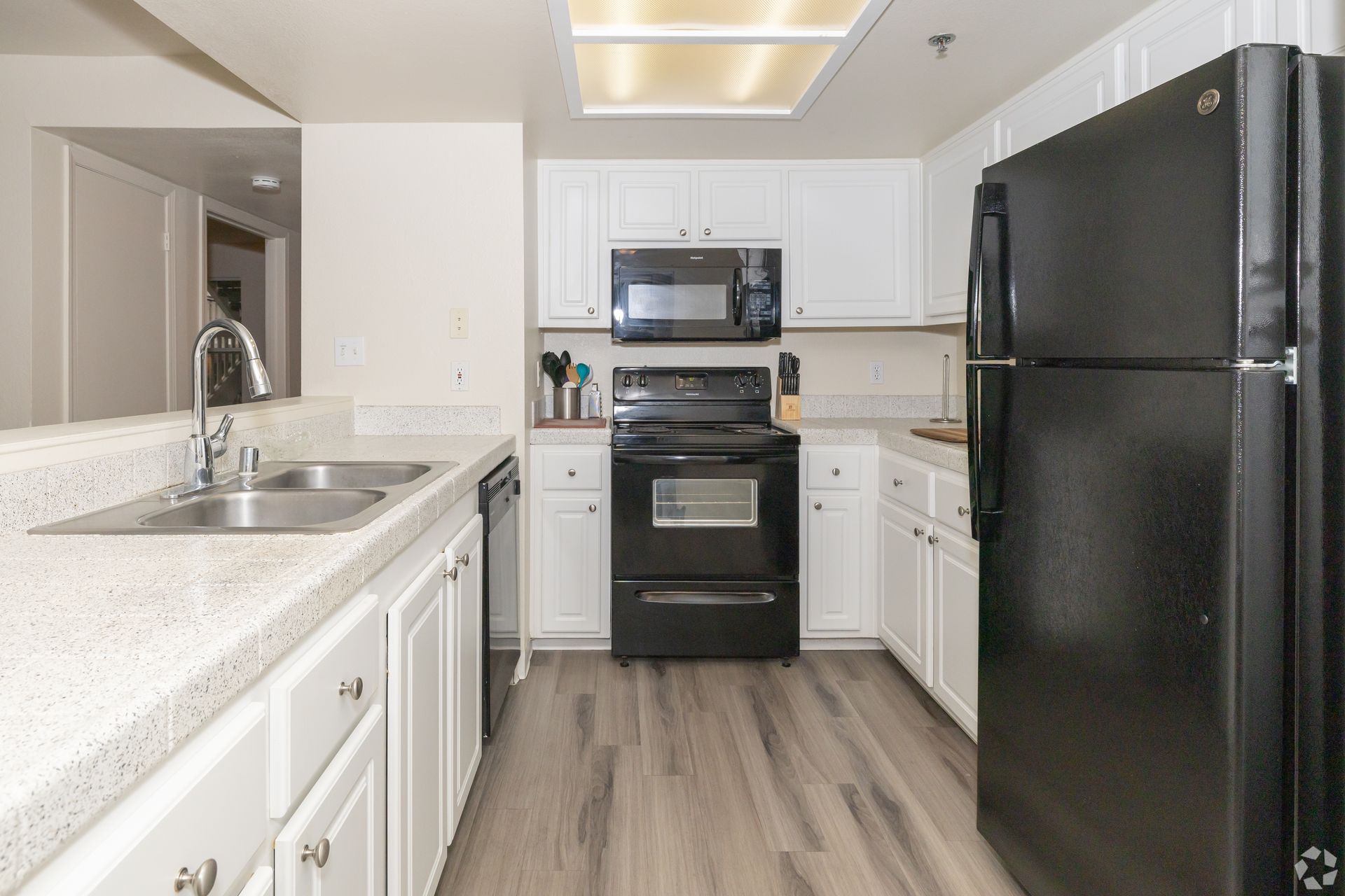 Kitchen with white cabinets, black appliances, and light countertops.